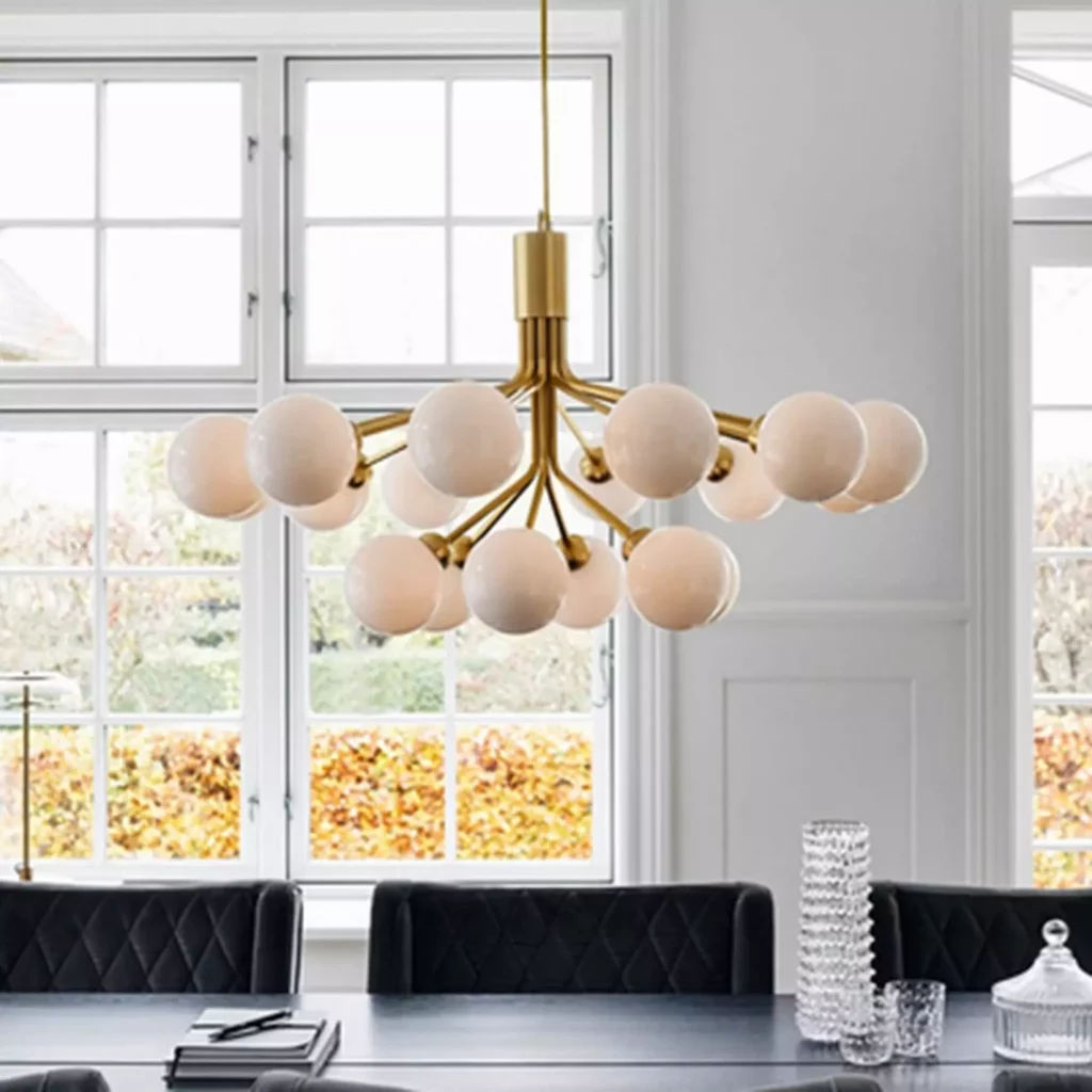 A modern Magic Bean Molecular Arm Apiales Chandelier with gold finish and white globe bulbs over a stylish dining table.