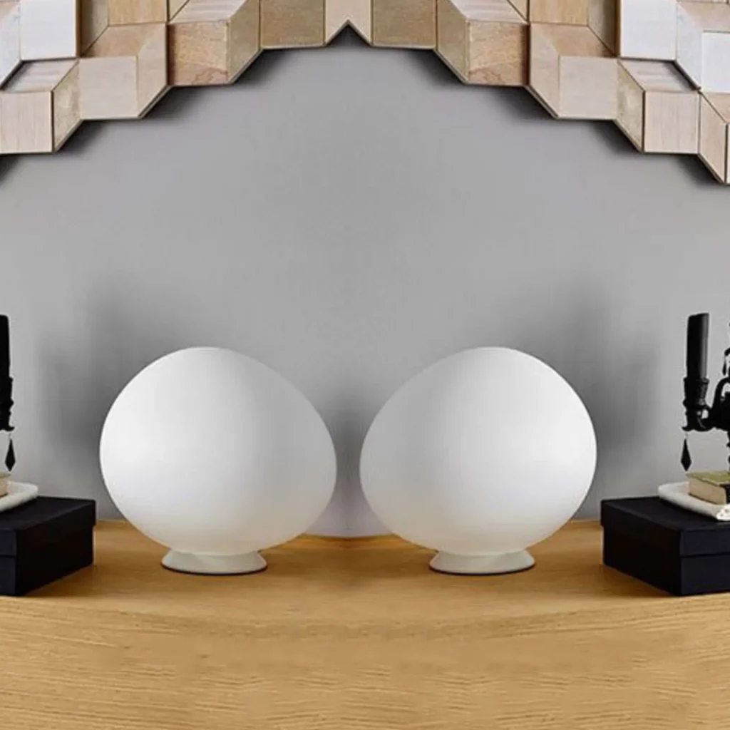 Gregg Table Lamp shown as two frosted oval glass lamps on a wooden table emitting a soft organic glow in a minimalist setting