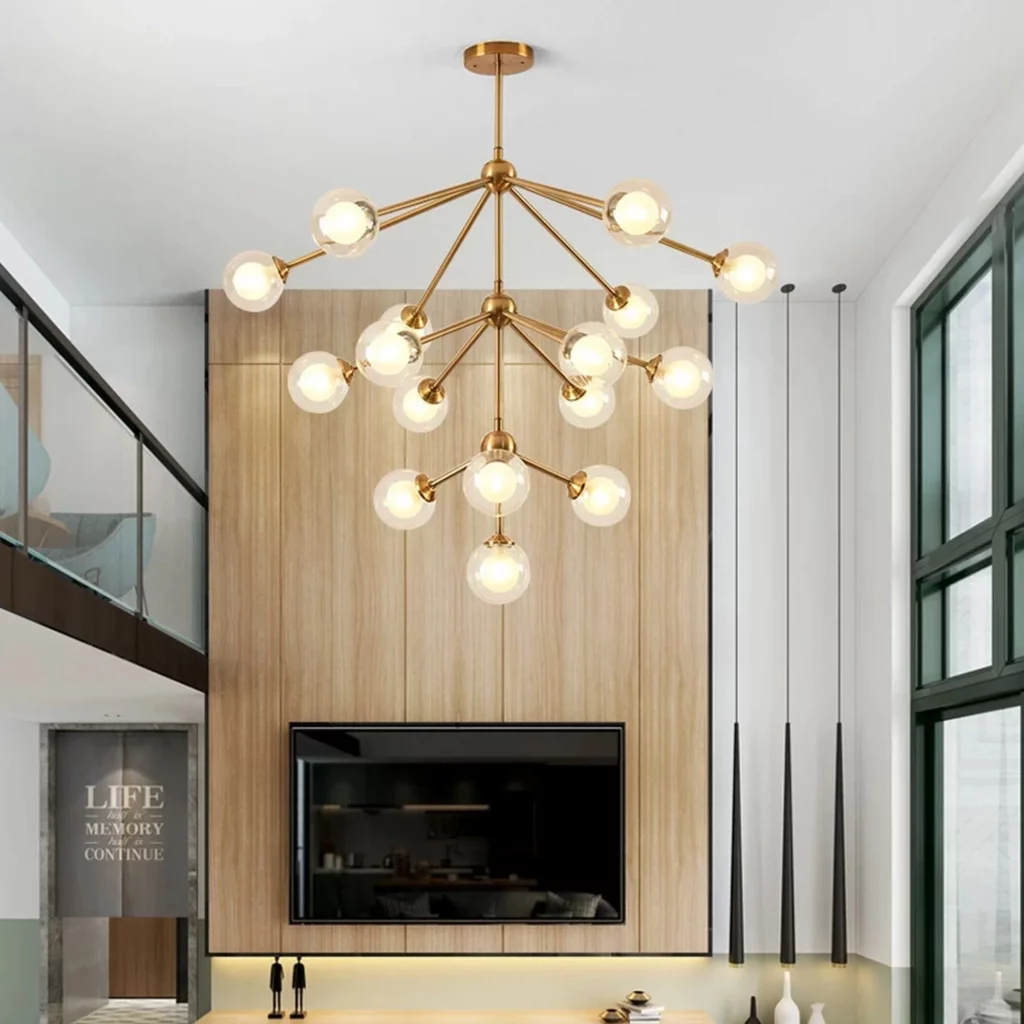 A Nordic Tree Branch Rustic Chandelier with gold finish and clear glass globes illuminates a modern living room with wood panels.