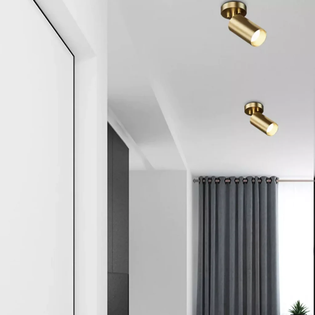 Pair of minimalist surface mounted ceiling spotlights in a brushed gold finish set against a clean white ceiling
