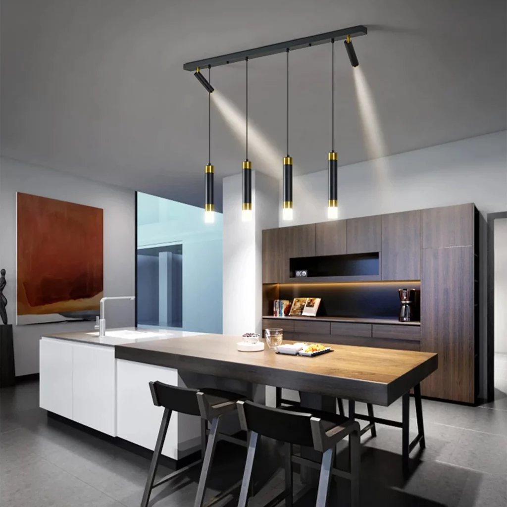 Industrial style kitchen island lighting featuring four black and gold pendant cylinders and two angled track spotlights