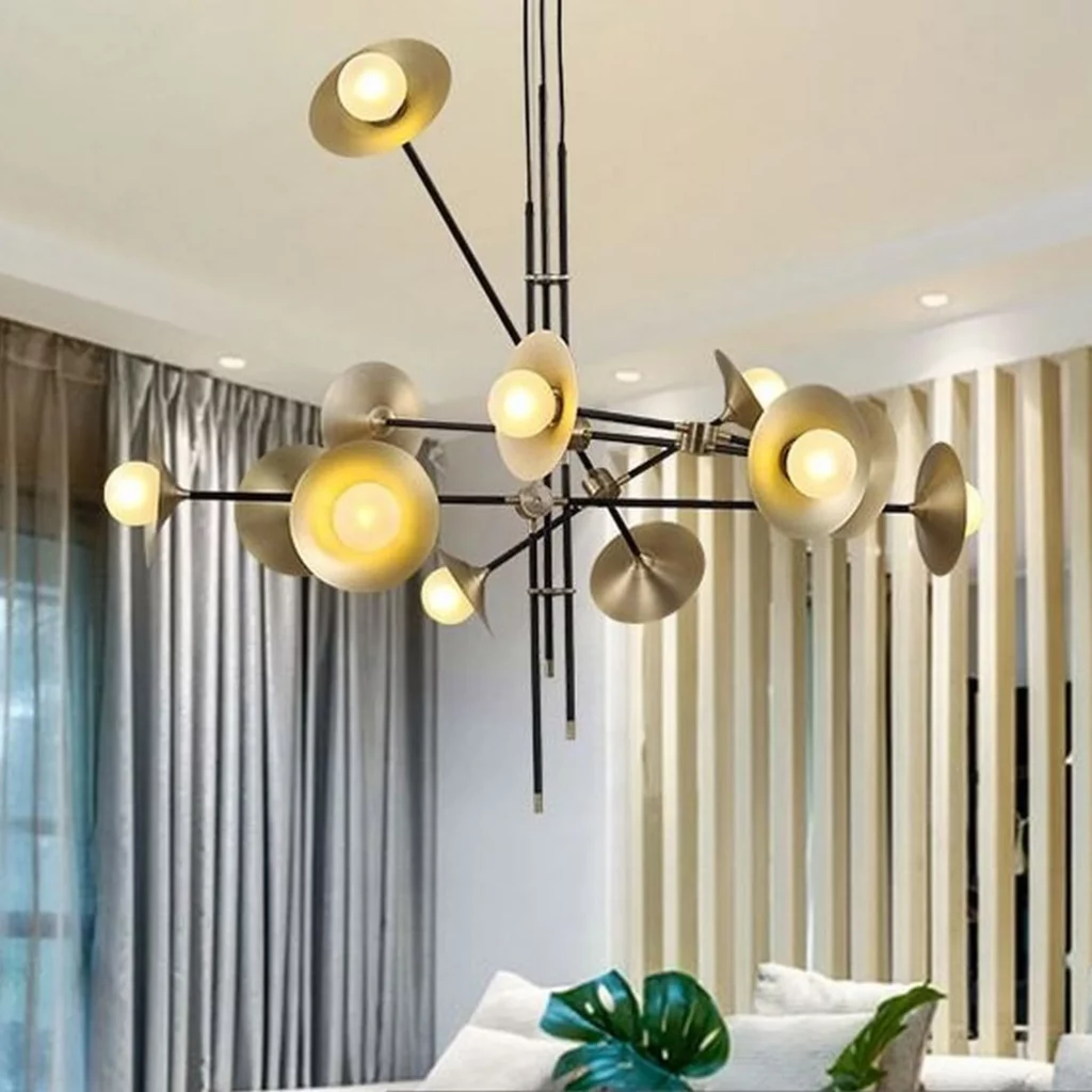 A modern Cymbals Branch Chandelier featuring black rods and gold-toned disc shades illuminated in a bright, contemporary living room.