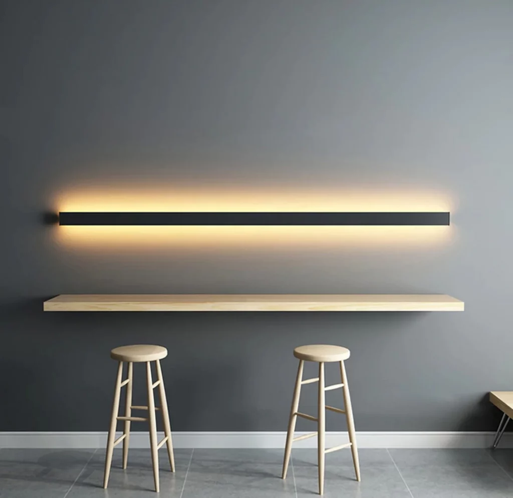 Black Long Rectangle Bar LED Wall Lamp with a sleek design, casting soft light over minimalist stools and a simple wooden counter.