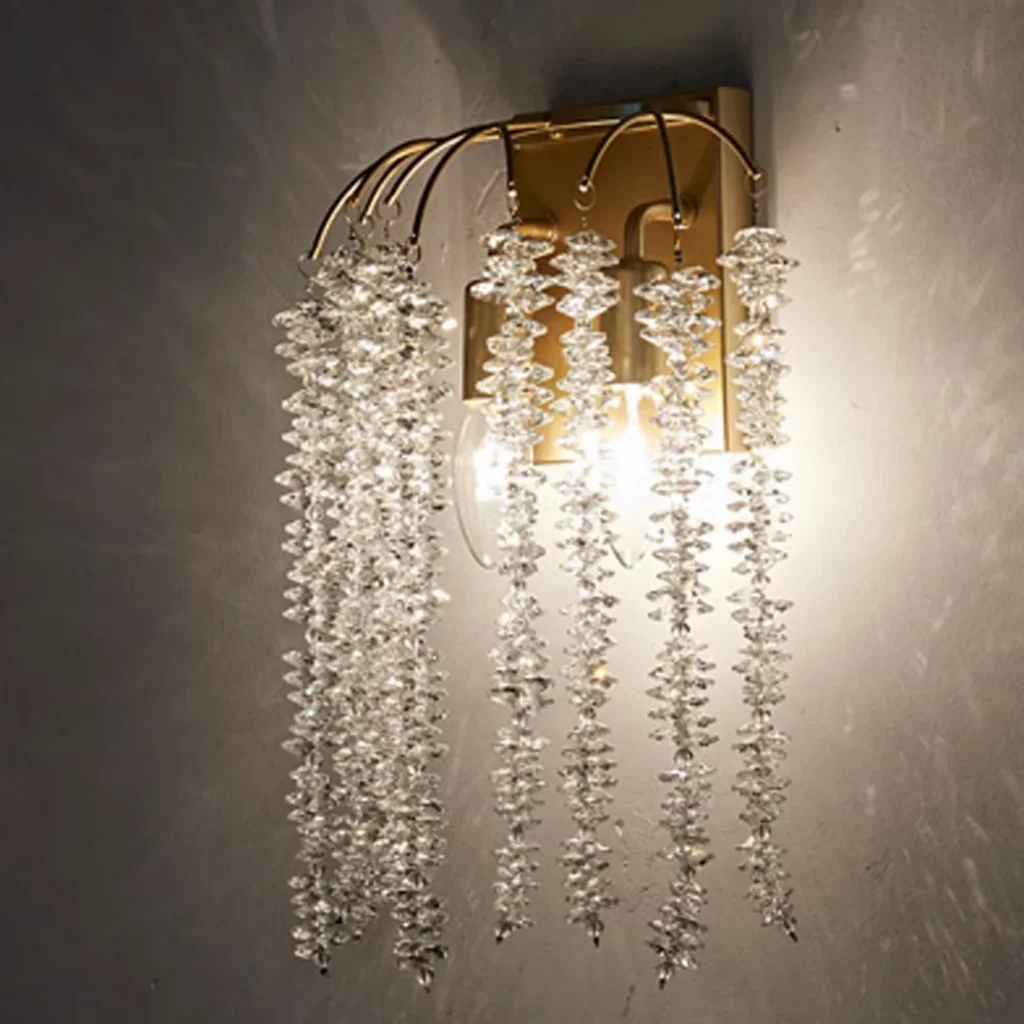 Crystal Hanging Design Wall Lamp with cascading crystal strands and warm glow, mounted on a gold base, elegant and modern lighting.