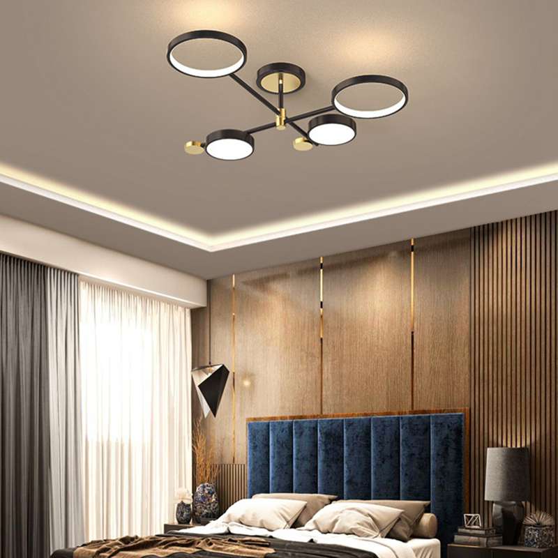 Modern Ring Design Black Gold LED Chandelier with four circular lights on a black frame illuminating a luxury bedroom with blue headboard