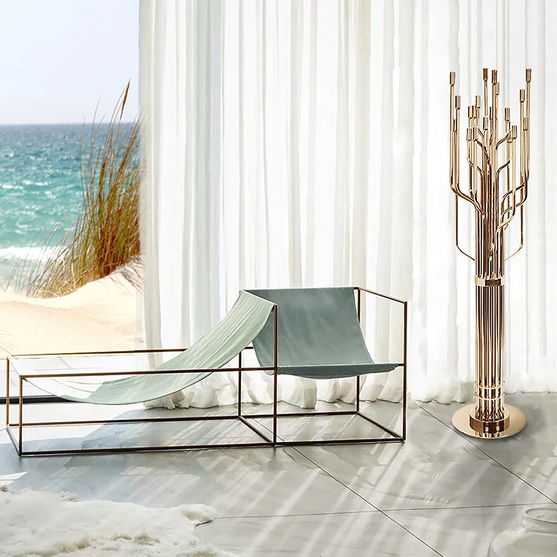 Gold Tree Design Luxury Floor Lamp standing beside minimalist lounge seating in a bright coastal room with sheer curtains and an ocean view.