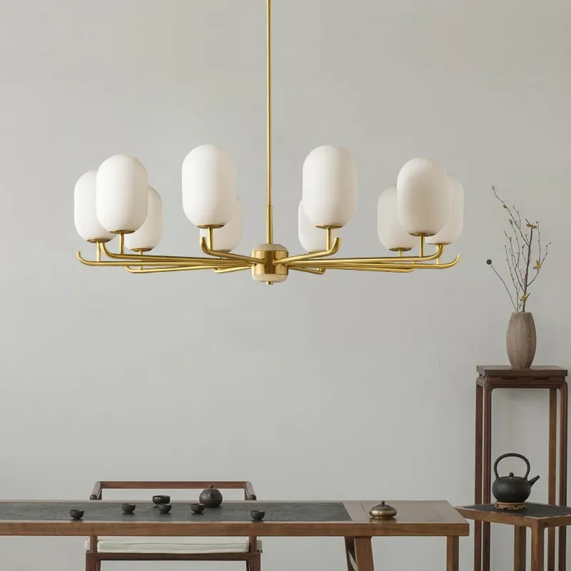 Modern Geometric Design Branch Chandelier with gold metal arms and white glass globes hanging over a traditional wooden tea table.