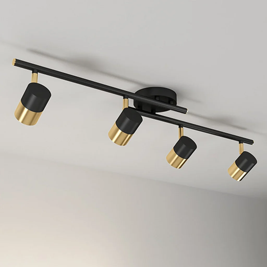 Modern surface mounted track light with four rotatable cylindrical heads in a sophisticated black and gold finish