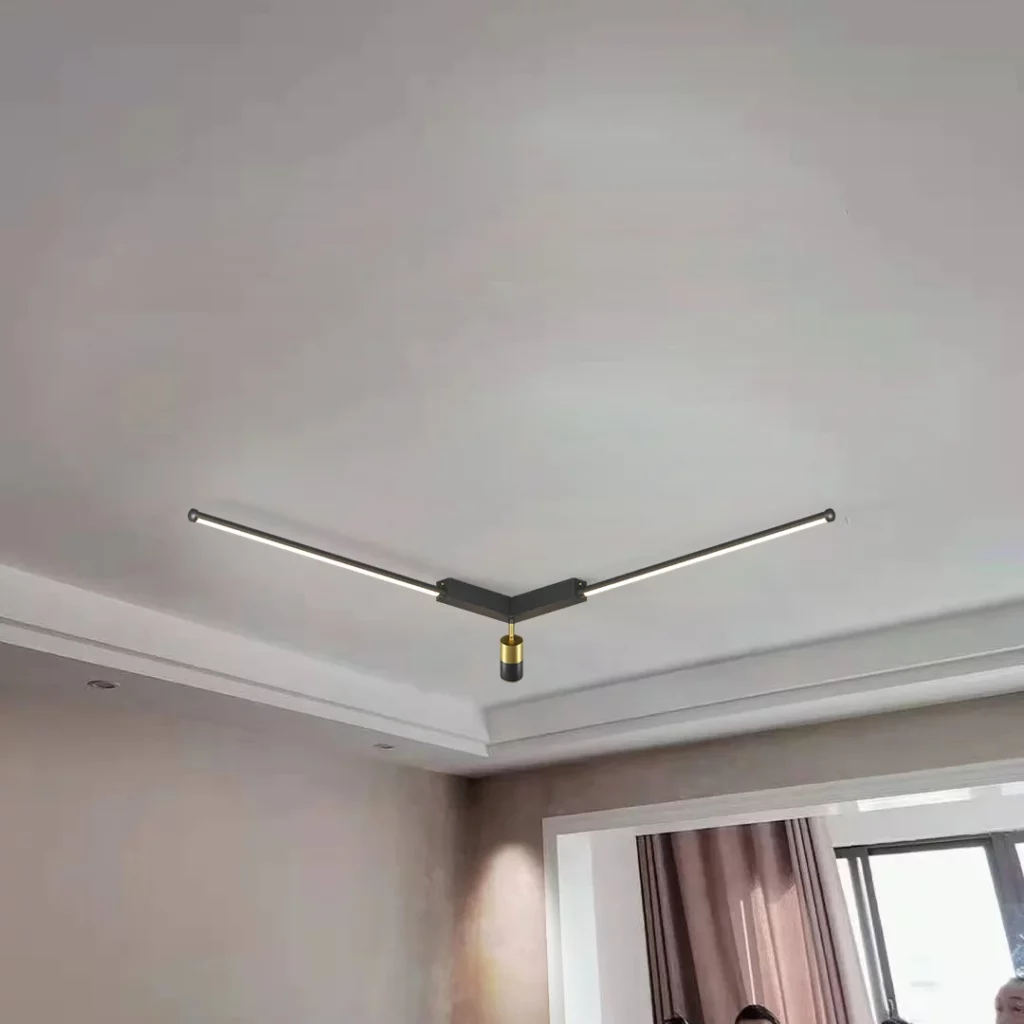 Minimalist black V shaped magnetic track light featuring slim LED bars and a single gold accented spotlight in a white room