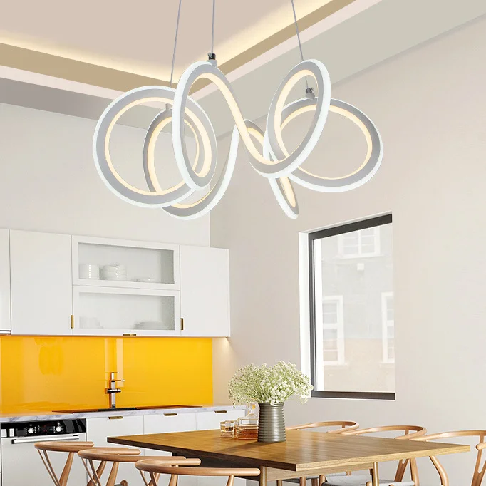 White Spiral Design LED Chandelier with interlocking glowing white rings emitting soft yellow light. Modern abstract fixture features twisted circular hoops suspended from ceiling against neutral gray background.