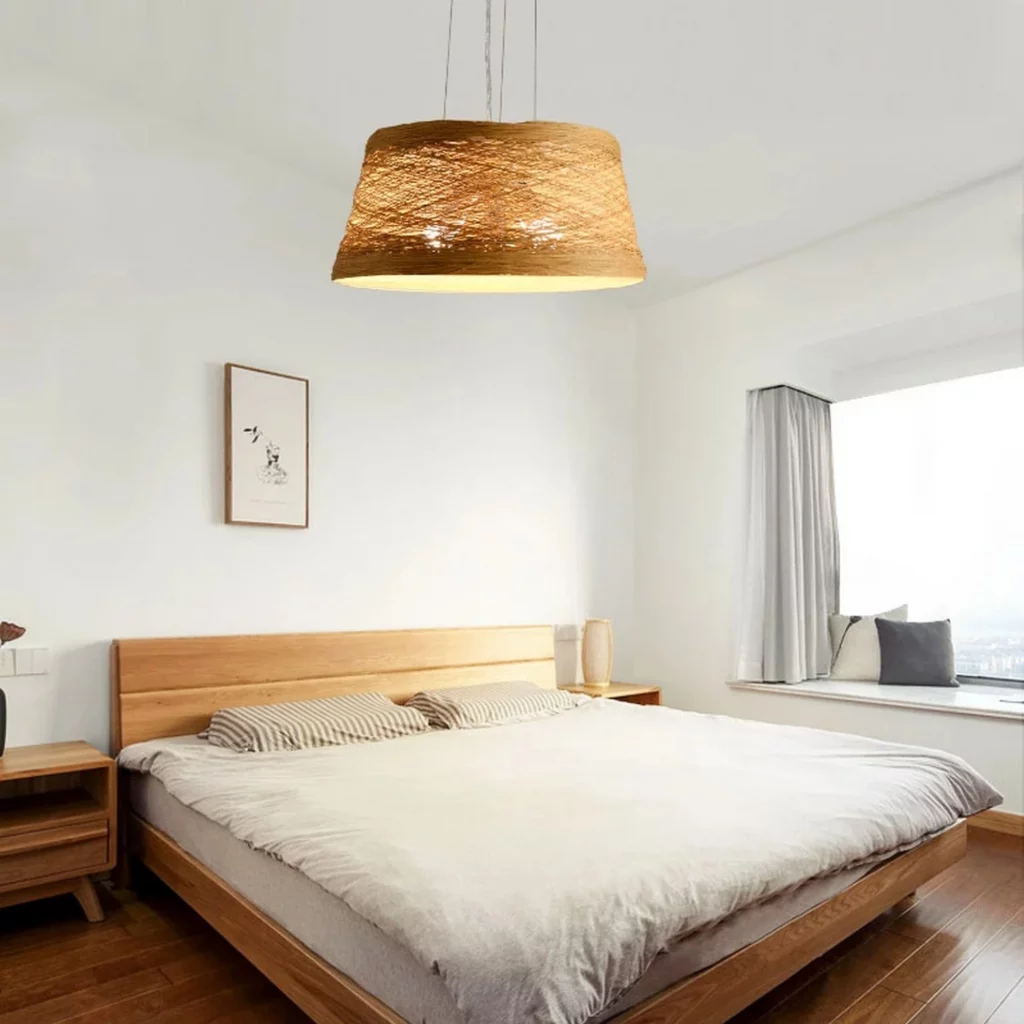 Simple Rattan Wooden Pendant Light above a wooden bed in a bright minimalist bedroom.