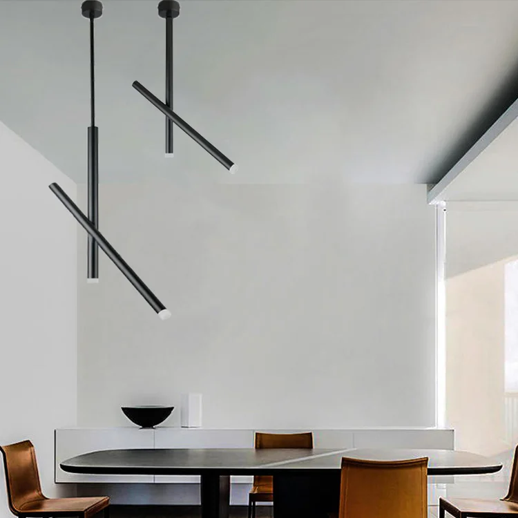 Minimalist dining room featuring two black pendant lights with a sculptural intersecting tube design over a long table