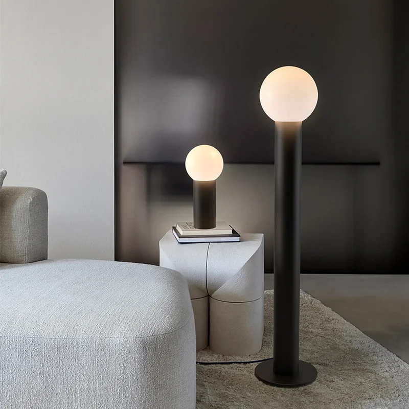 Modern black Uplight Floor Lamp with glowing globe shade beside matching table lamp in minimalist living room with neutral decor
