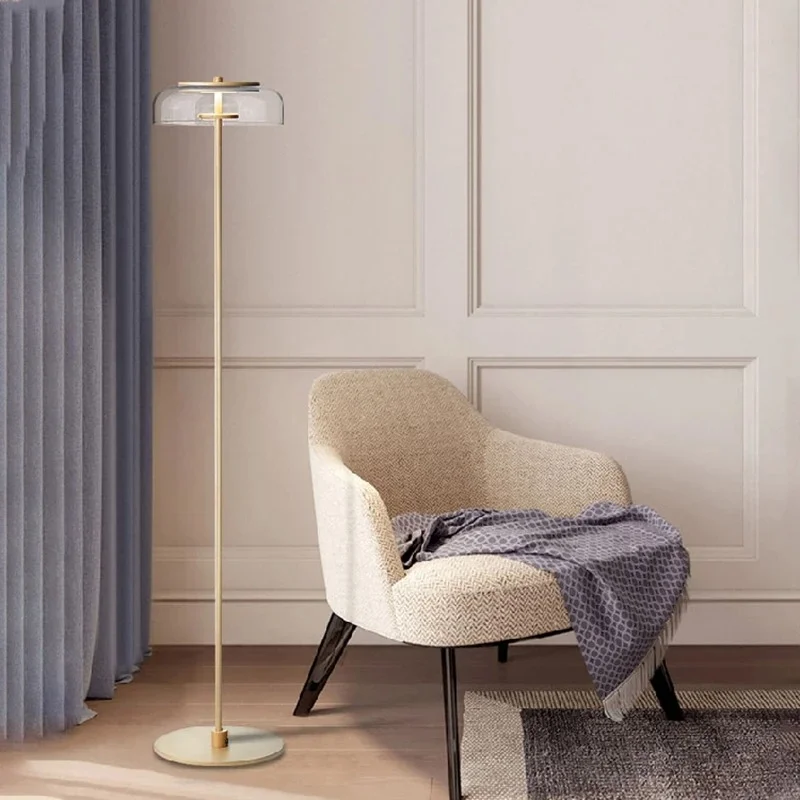 A cozy corner featuring a modern chair with a blanket and a Blossi Floor Lamp beside it, adding stylish lighting to the room.
